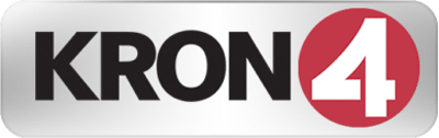 Logo of KRON 4, featuring "KRON" in black letters and a red circle with a white number "4" inside against a metallic rectangular background.