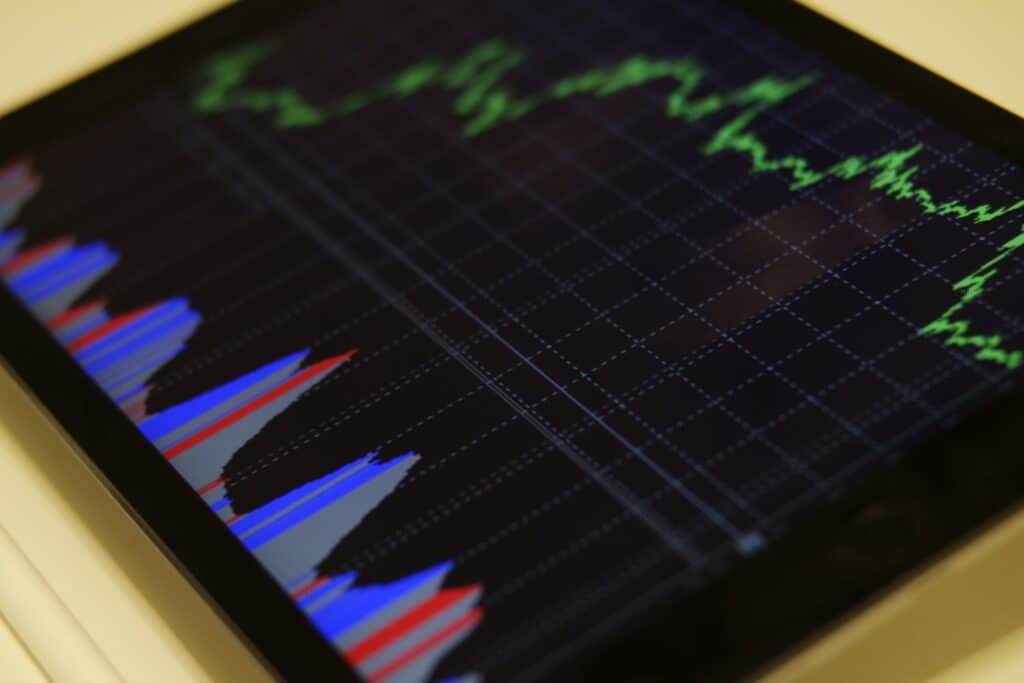 A tablet screen displaying a line graph with green lines and bar charts in blue, red, and gray sections.