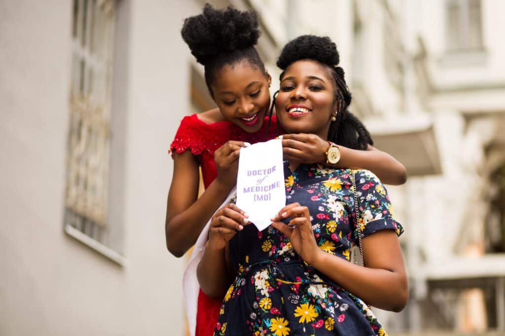 Two women are standing on a sidewalk.