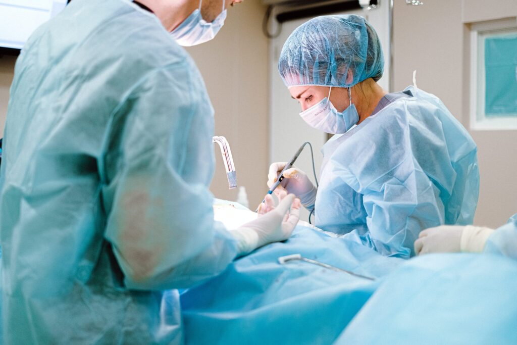 Surgeons in blue scrubs and masks perform a surgical procedure in an operating room.