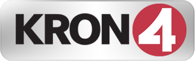 Logo of KRON 4, featuring "KRON" in black letters and a red circle with a white number "4" inside against a metallic rectangular background.