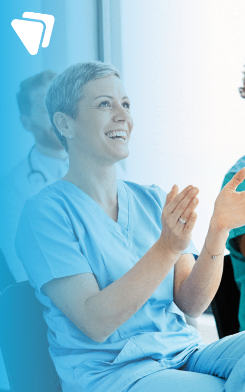 Female doctor with short hair engaging in a meeting and smiling wearing scrubs
